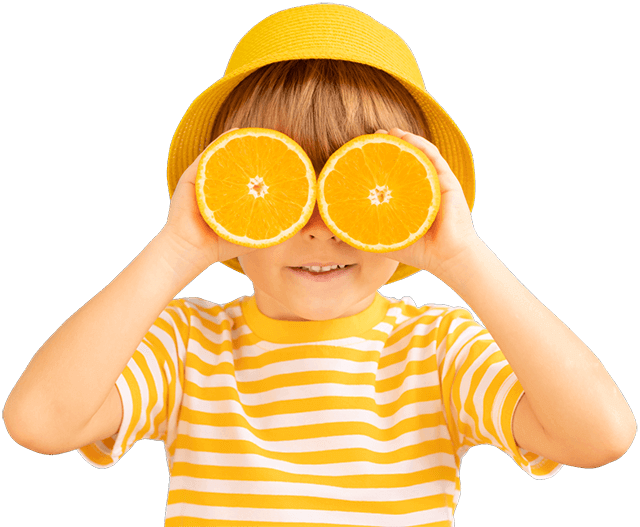 Happy child with oranges holding them up to eyes like glasses